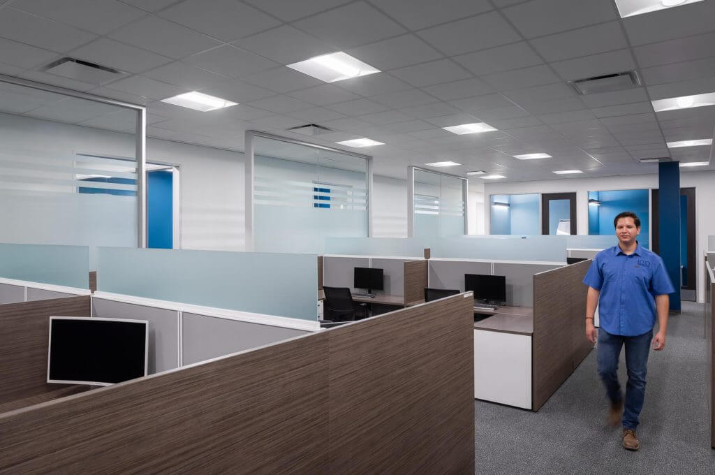 Employee walking through Cellipont Bioservices’ open-plan office space, featuring collaborative workstations and modern infrastructure supporting cell therapy operations.