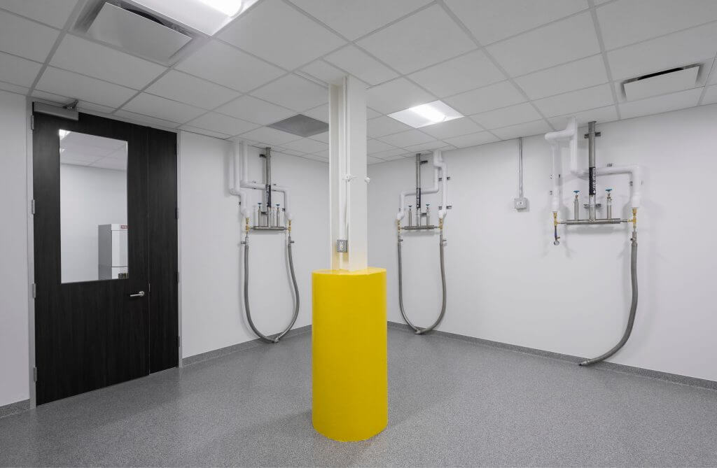 Utility hook-up room in a GMP biomanufacturing facility featuring cleanroom-grade gas and fluid line connections for cell therapy production systems.
