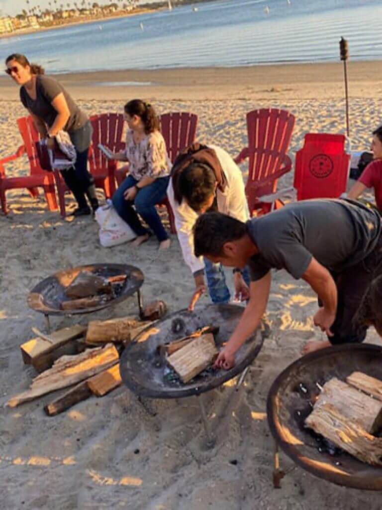 Cellipont team members enjoying a casual beach gathering with fire pits and ocean views, highlighting company culture and team-building activities.